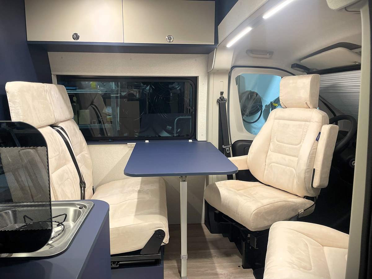 Ducato mit Hubbett, Fiat Ducato, Vordere Sitzgruppe mit Tisch und blauen Polstern