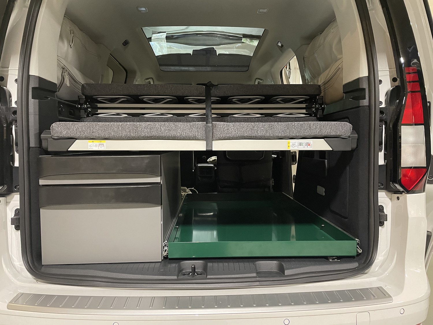 Heck eines VW Caddy mit Bettplattform und eingeschobenem grünem Auszug