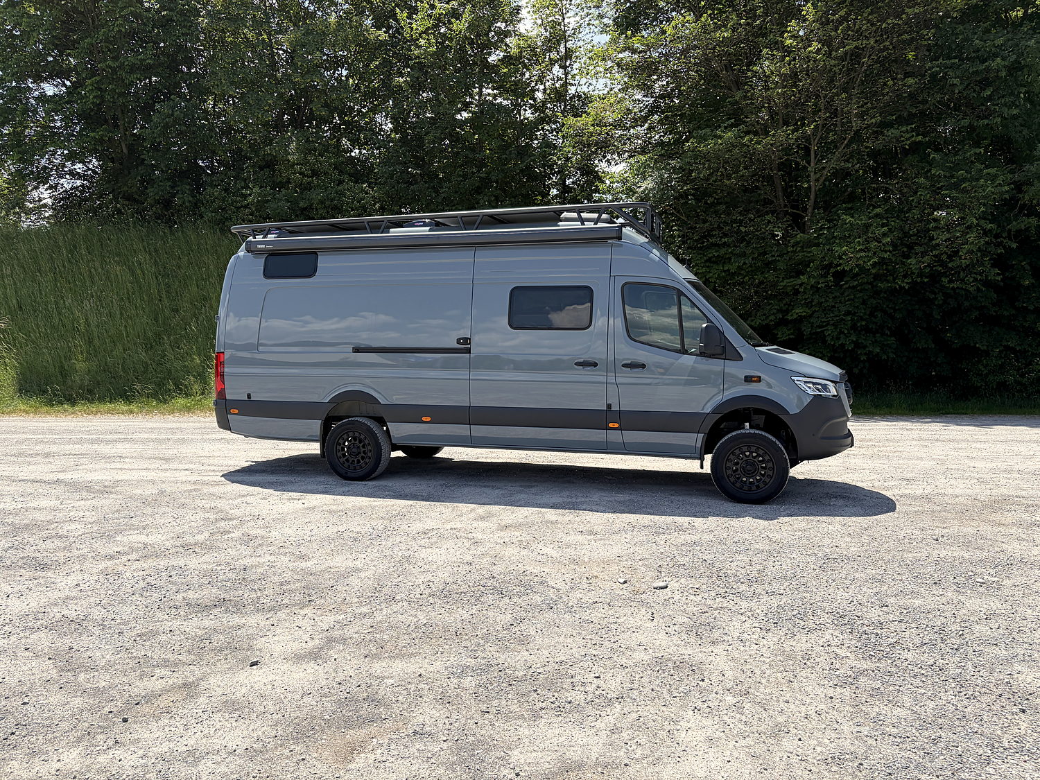 El Grisito, Mercedes Sprinter 4×4, Seitenansicht auf Kies vor Bäumen