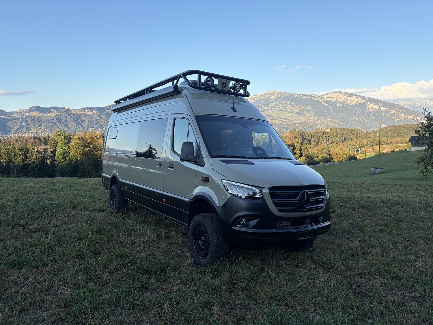 Sandfarbener Mercedes Sprinter vor einer Bergkulisse