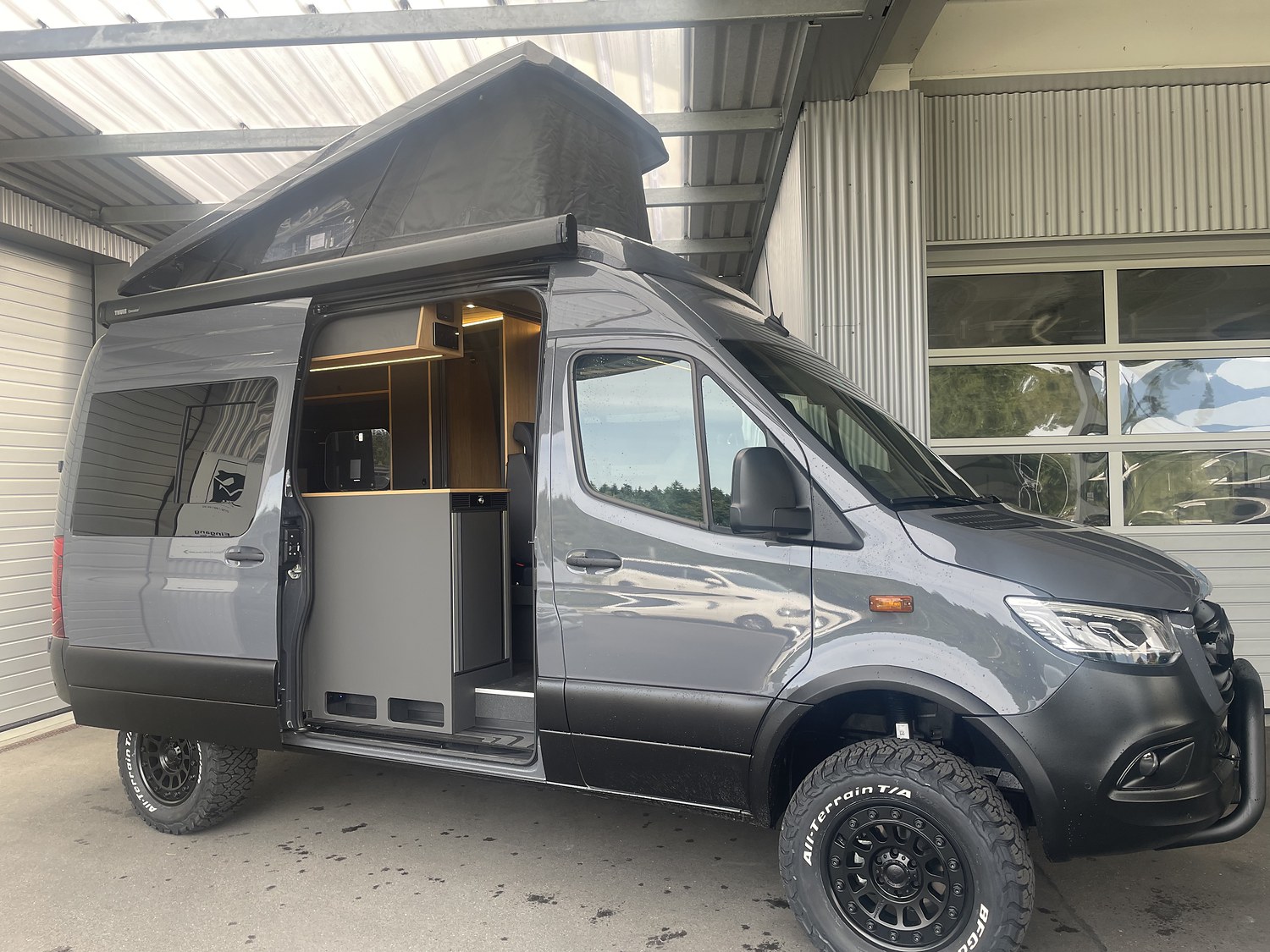 Grauer Mercedes Sprinter mit geöffnetem Schlafdach und Schiebetür